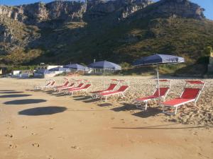 een rij stoelen en parasols op een strand bij DEPANDANCE SUL MARE in Sperlonga