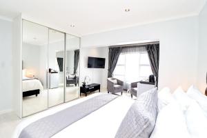 a white bedroom with a large white bed and mirror at Augusta Palms in Centurion