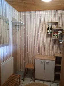 a bathroom with a wooden wall with a shelf with bottles at Ferienwohnung Tuchscherer in Cranzahl