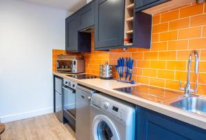 a kitchen with a washer and dryer next to a sink at Southgate Coach House in Dorchester