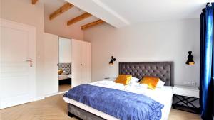 een slaapkamer met een bed met een blauw dekbed en oranje kussens bij Apartamenty Royal Maris 4 - najlepsza lokalizacja w Ustce, blisko plaży i portu, bezpłatny parking, ścicsłe centrum in Ustka