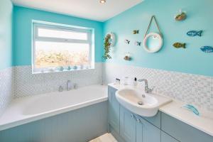 a blue bathroom with a sink and a bath tub and a window at Host & Stay - The Beach House in Marske-by-the-Sea