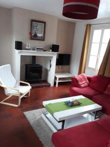 sala de estar con sofá rojo y chimenea en L'escale Arquaise, la maison au jardin fleuri à 5 min de dieppe en Arques-la-Bataille