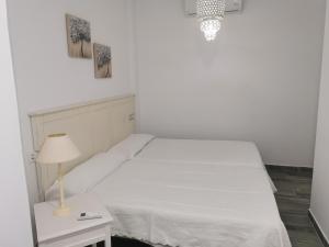 a bedroom with a white bed and a table with a lamp at Apartamentos Sanlúcar Beach 4 y 5 in Sanlúcar de Barrameda