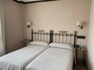 two beds in a bedroom with white sheets at Hotel Los Molinos in Llanes