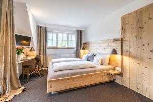 a bedroom with a large wooden bed and a desk at Hotel Blaue Gams ***S in Ettal