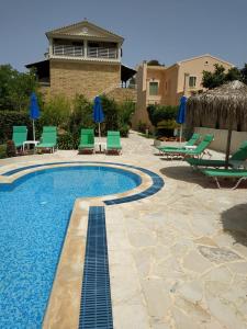 a swimming pool with lawn chairs and blue umbrellas at Lena Studios in Sidari