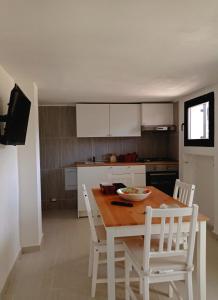 una cucina con tavolo in legno e sedie bianche di Marina Piccola Apartment a Bari