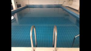 a swimming pool with a blue tile floor and metal rails at Ein Zimmer Apartment Bernau mit großer Garage incl in Bernau am Chiemsee