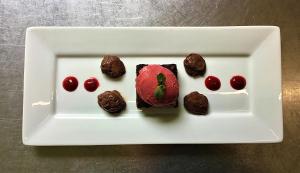 Un plato blanco con galletas de chocolate y cerezas. en Auberge de la Sagne en Cabrerets