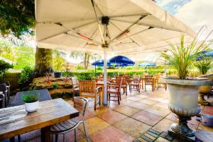 a patio with tables and chairs and an umbrella at Inn in the Park in Bournemouth