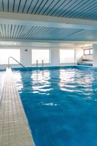 a swimming pool with blue water in a building at Ein Zimmer Apartment Bernau mit großer Garage incl in Bernau am Chiemsee