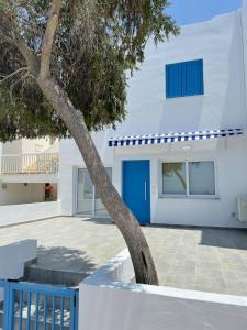 a white house with a blue door and a tree at Ikaria Village Maisonette 12 in Paphos