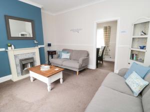 a living room with a couch and a table at Sandy Toes Cottage in Newbiggin-by-the-Sea