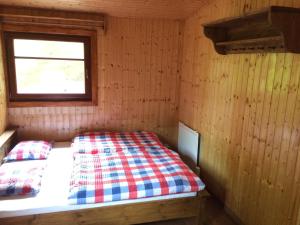 a bed in a wooden room with a window at Chata Sklene Teplice in Sklené Teplice