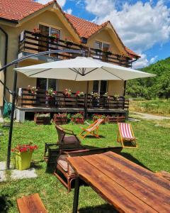 a house with a bench and an umbrella in the yard at Vila Vrh in Crni Vrh