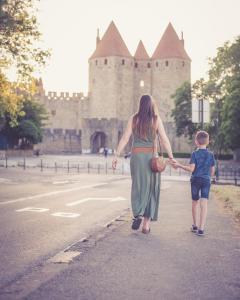 a woman and a child walking down a street with a castle at 514 Appart Hotel in Carcassonne