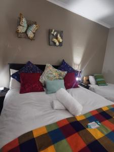 een slaapkamer met een bed met kleurrijke kussens erop bij Harties 2 Sleeper Double Room with Private Bathroom in Hartbeespoort