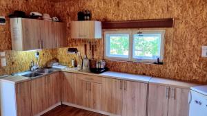 a kitchen with wooden cabinets and a window at Domek Łukaszówka in Jonkowo