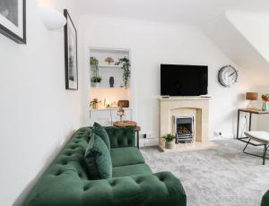 a living room with a green couch and a fireplace at Tweed Bank in Lundin Links