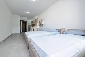 two beds in a room with white walls at Apartmani Divna in Neum