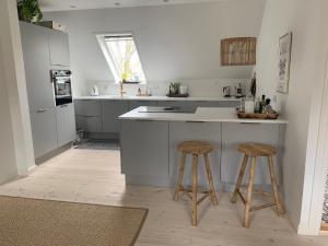 a kitchen with a counter and two stools at Renovated villa with private garden in Rungsted