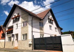 a white house with flower boxes on the windows at Pensiunea Aliart in Zărneşti