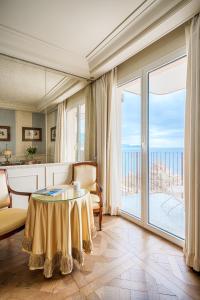 a living room with a table and a large window at Excelsior Palace Portofino Coast in Rapallo