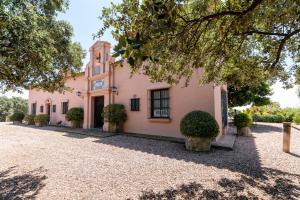 a pink building with a clock tower on it at Casa Alta Finca El Revuelo in Las Navas de la Concepción