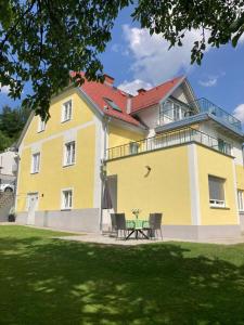 a yellow building with chairs and a table in front of it at Gästehaus Landgraf in Übelbach