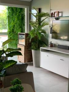 a living room with a tv and some plants at Flat Fabuloso 808 Villa Hípica in Gravatá