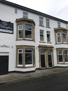 a white building with windows and doors on a street at The Wellington House Hotel in Blackpool