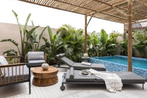 eine Resortterrasse mit Pool, Stühlen und einem Tisch in der Unterkunft NOW-VX adults only in Eilat