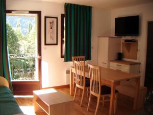 uma sala de estar com mesa e cadeiras e uma janela em Les jardins Ramel em Luchon