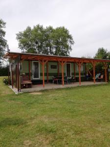 una casa verde con porche y césped en Domek holenderski, en Gawliki Wielkie