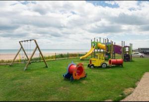 a playground with a slide and a swing set on the grass at Savannah-by-the-sea in Bridlington