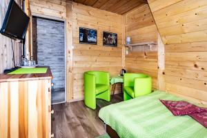 ブコビナ・タトシャンスカにあるWilla Majka - Bukowina Tatrzańskaのベッド1台と緑の椅子2脚が備わる客室です。