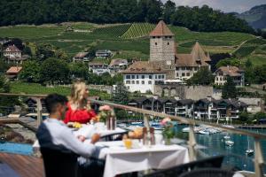 施皮茨的住宿－Belvédère Strandhotel，坐在俯瞰河流的餐厅桌子上的男女