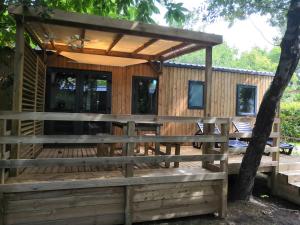a house with a wooden deck with a pergola at Mobil Home Camping Mayotte Biscarrosse in Biscarrosse