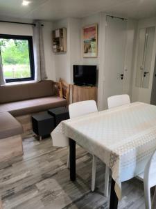 a living room with a table and chairs and a couch at Mobil Home Camping Mayotte Biscarrosse in Biscarrosse