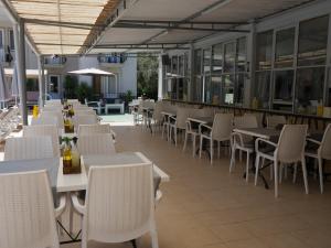 Nefis Hotel Ölüdeniz في أولدينيس: مطعم بطاولات بيضاء وكراسي ومسبح