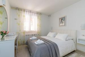 een witte slaapkamer met een bed en een raam bij Apartments Lavizatic in Poreč