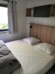 a bed with two pillows on it in a bedroom at Mobil Home Camping Mayotte Biscarrosse in Biscarrosse