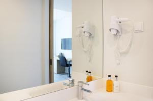 a bathroom sink with a mirror and a hair dryer at AP Cabanas Beach & Nature - Adults Friendly in Cabanas de Tavira