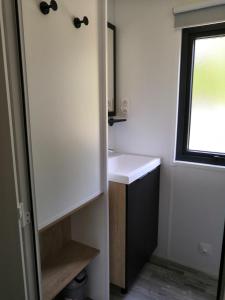 a bathroom with a white sink and a window at Mobil Home Camping Mayotte Biscarrosse in Biscarrosse