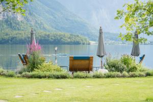 a lake with two umbrellas and a person on a boat at Glück am See - Apartment mit Seezugang in Hallstatt