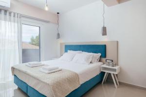 a bedroom with a blue and white bed and a window at Corner45 Apartments in Kalamaki