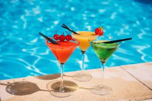 three cocktails on a table next to a swimming pool at AP Cabanas Beach & Nature - Adults Friendly in Cabanas de Tavira