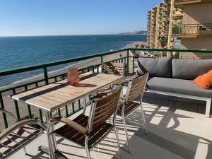 een tafel en stoelen op een balkon met uitzicht op de oceaan bij Beachfront apartment in Fuengirola in Fuengirola