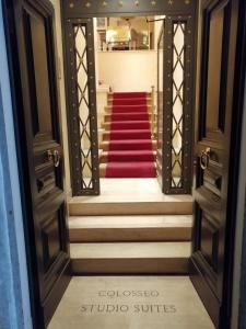 einen Blick durch eine offene Tür einer Treppe mit einem roten Teppich in der Unterkunft Colosseo Studio Suite in Rom